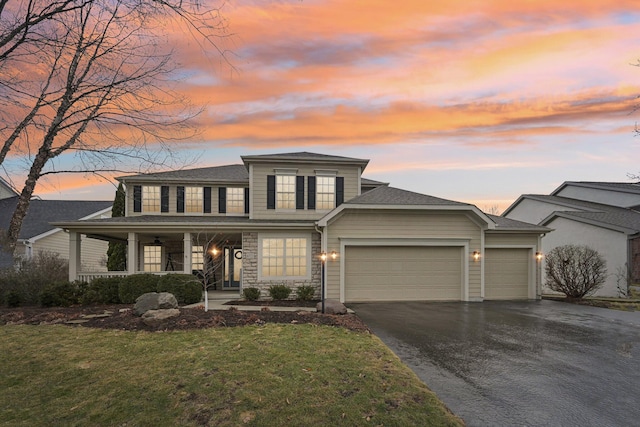 view of front of home featuring driveway, covered porch, a garage, and a front lawn