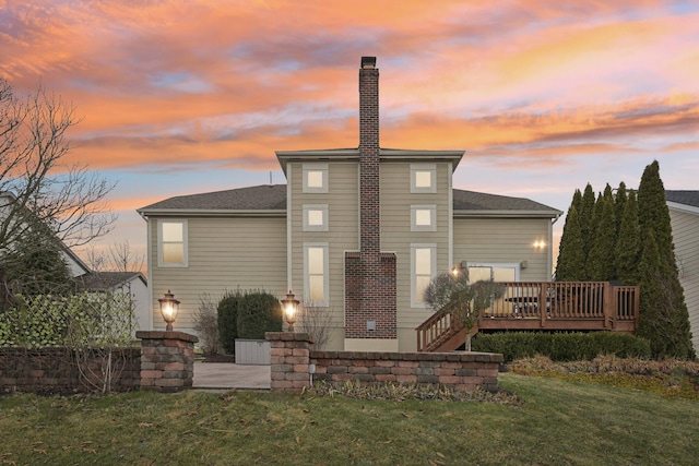 back of house featuring a deck, a yard, and a chimney