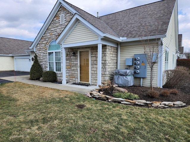 view of front of house featuring a garage, stone siding, a shingled roof, and a front lawn