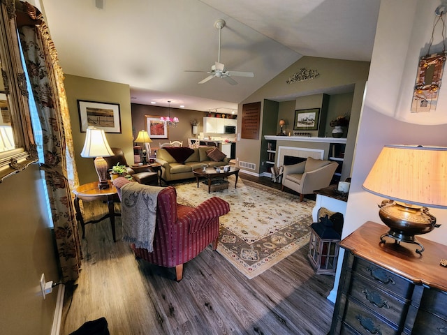 living area with visible vents, a ceiling fan, wood finished floors, vaulted ceiling, and a fireplace