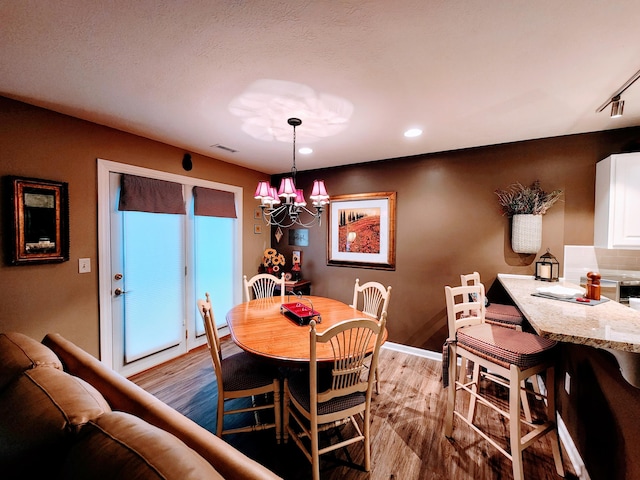 dining space with an inviting chandelier, light wood-style flooring, visible vents, and recessed lighting