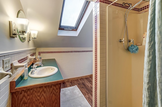 full bathroom with vaulted ceiling with skylight, wainscoting, a shower with shower curtain, wood finished floors, and tile walls