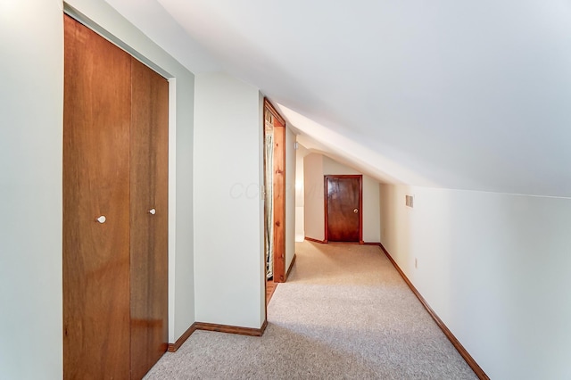 hall featuring light carpet, vaulted ceiling, and baseboards