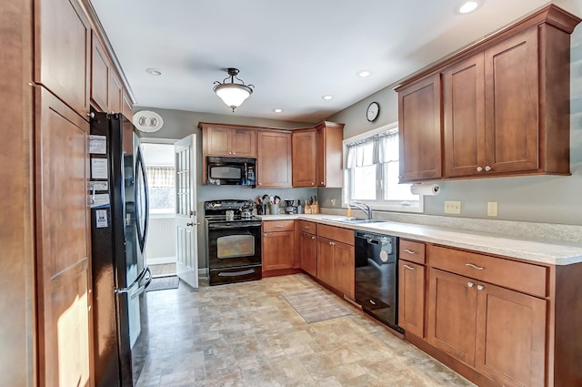 kitchen featuring black appliances, brown cabinetry, a sink, and recessed lighting