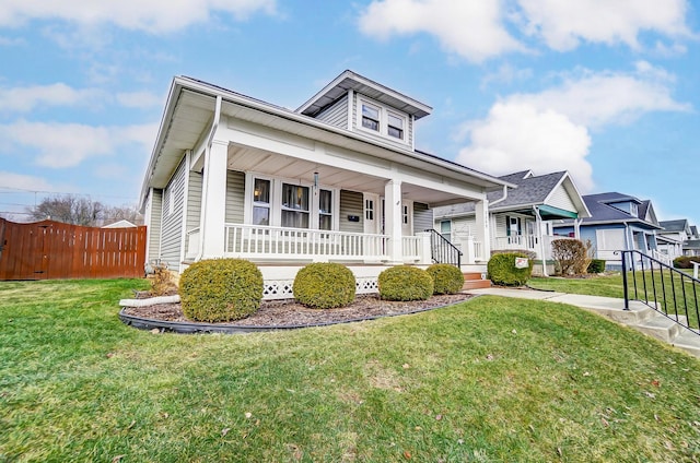 bungalow featuring covered porch, fence, and a front lawn