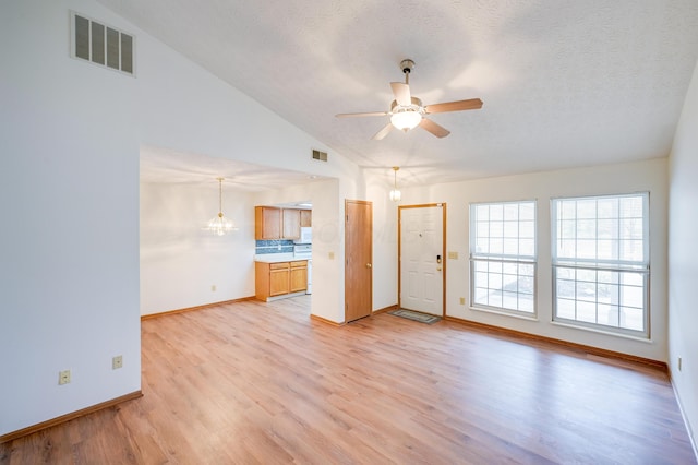 unfurnished living room featuring light wood-type flooring, visible vents, vaulted ceiling, and ceiling fan with notable chandelier