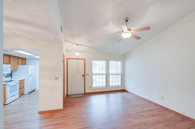 interior space with a textured ceiling, ceiling fan, lofted ceiling, baseboards, and light wood-style floors