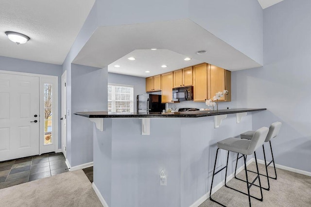 kitchen featuring black appliances, baseboards, and a breakfast bar