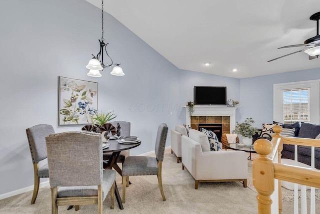 dining room featuring light carpet, baseboards, lofted ceiling, ceiling fan, and a fireplace