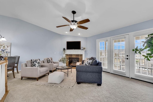 living area featuring carpet floors, lofted ceiling, a ceiling fan, and a tile fireplace