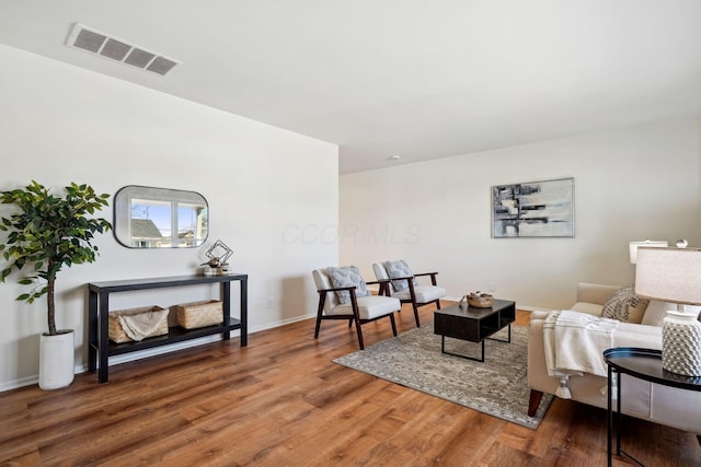 living area with wood finished floors, visible vents, and baseboards