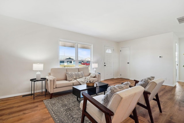 living area featuring visible vents, baseboards, and wood finished floors