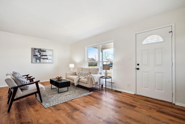 living room featuring wood finished floors, visible vents, and baseboards