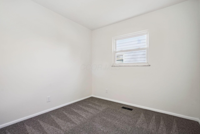 unfurnished room with dark colored carpet, visible vents, and baseboards