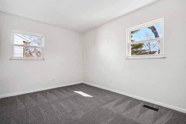 spare room featuring carpet flooring, visible vents, and baseboards