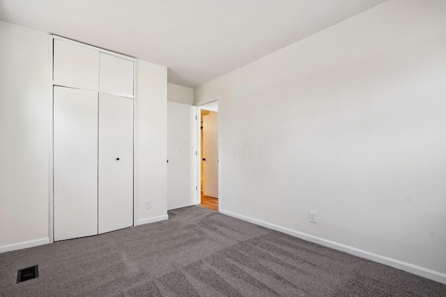 unfurnished bedroom featuring carpet, a closet, visible vents, and baseboards