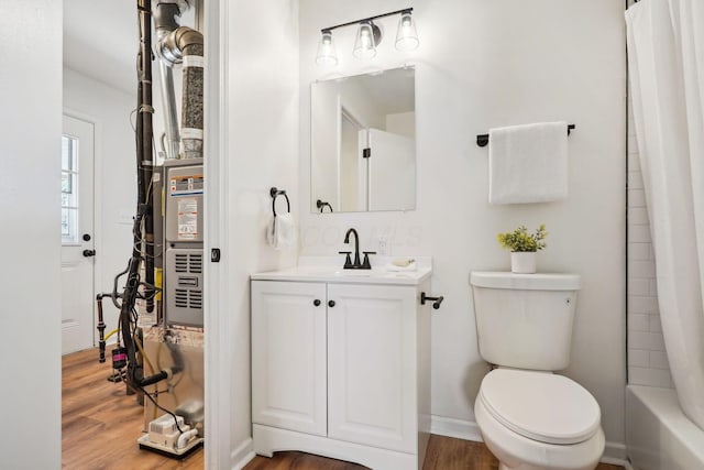 full bath featuring shower / bath combo, baseboards, toilet, wood finished floors, and vanity