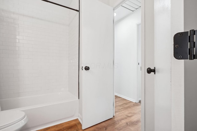 bathroom with shower / bathing tub combination, wood finished floors, and toilet