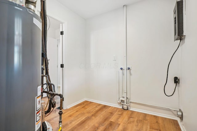 laundry room featuring baseboards, gas water heater, and light wood-style floors