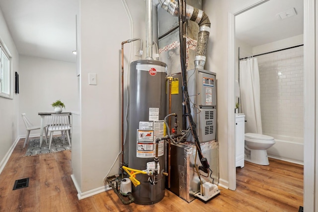 utilities with gas water heater, visible vents, and heating unit