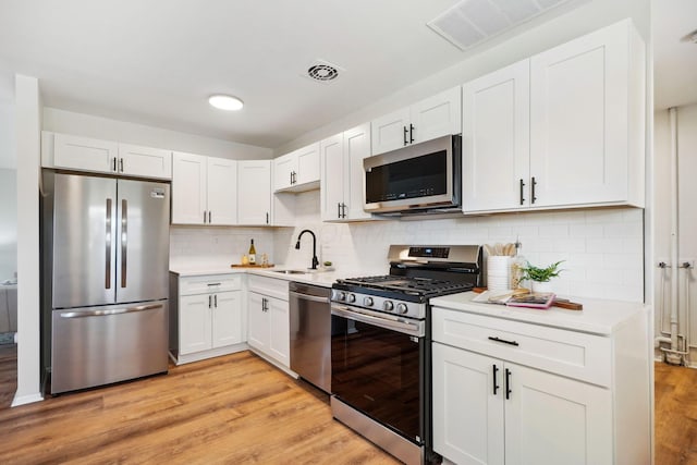 kitchen with light countertops, appliances with stainless steel finishes, a sink, and visible vents