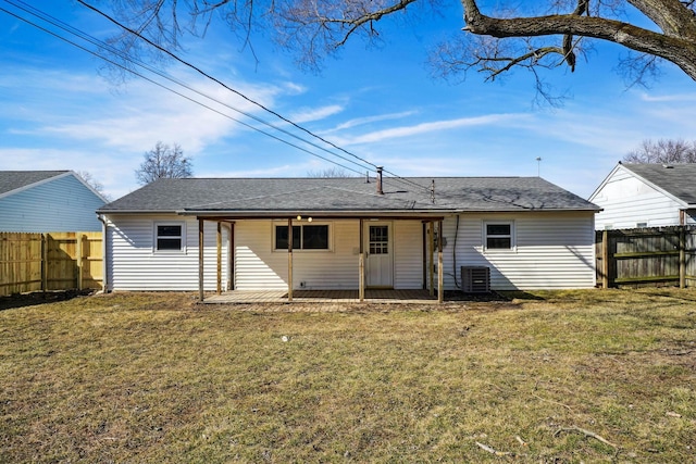 rear view of property with a lawn, fence, and central air condition unit