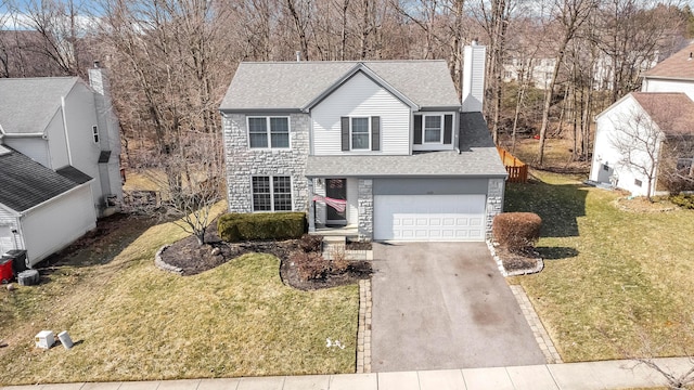 traditional-style home with driveway, a garage, a shingled roof, a chimney, and a front yard