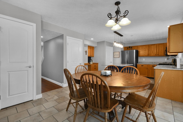 dining room with a notable chandelier, baseboards, a textured ceiling, and light tile patterned flooring