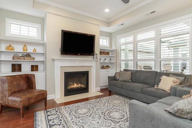 living area with ornamental molding, a fireplace, wood finished floors, and a wealth of natural light