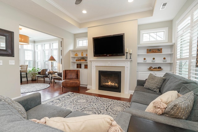 living room with a healthy amount of sunlight, visible vents, a raised ceiling, and wood finished floors