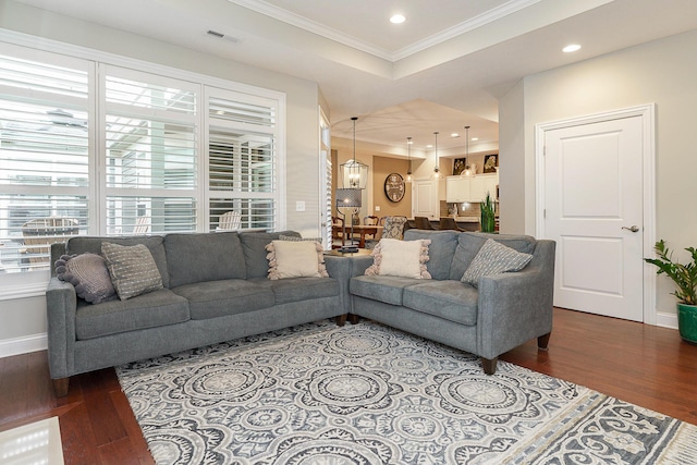 living area featuring a tray ceiling, ornamental molding, wood finished floors, and recessed lighting