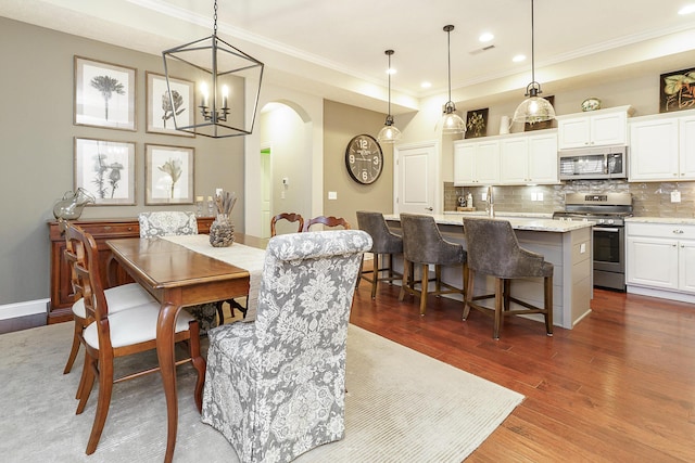 dining room featuring dark wood-type flooring, arched walkways, and crown molding