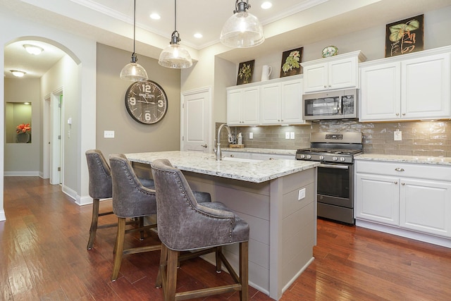 kitchen with stainless steel appliances, arched walkways, dark wood-type flooring, and backsplash