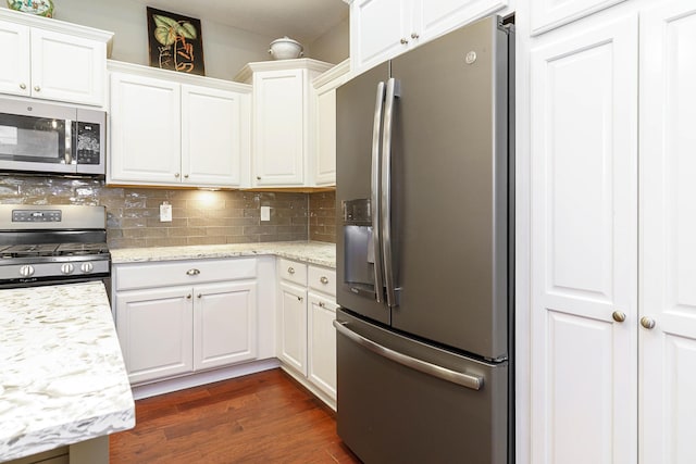 kitchen featuring tasteful backsplash, white cabinets, light stone counters, appliances with stainless steel finishes, and dark wood-type flooring