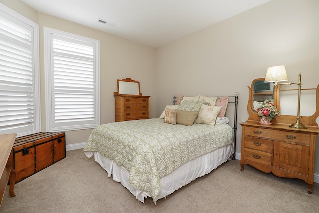 bedroom with baseboards, visible vents, and light colored carpet