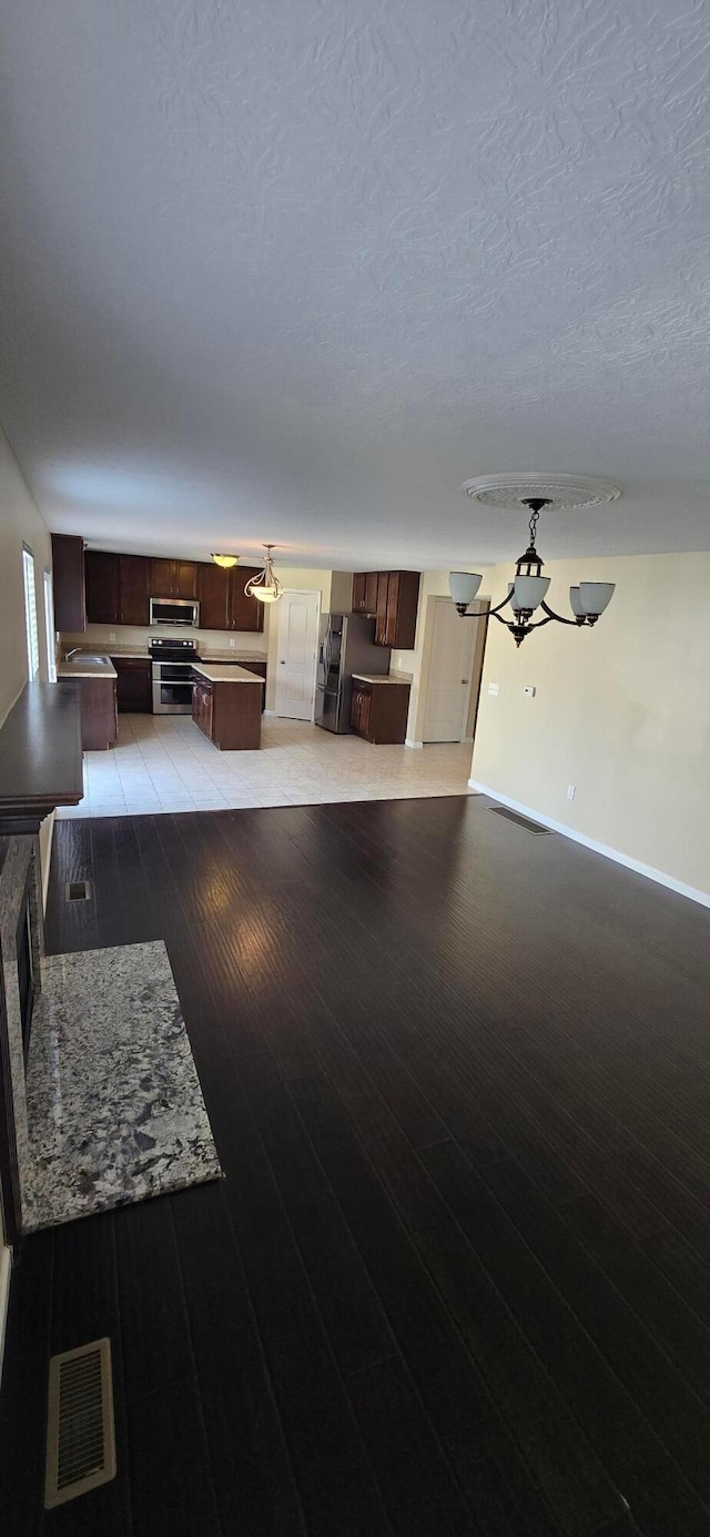 living area featuring a textured ceiling, light wood finished floors, visible vents, and baseboards