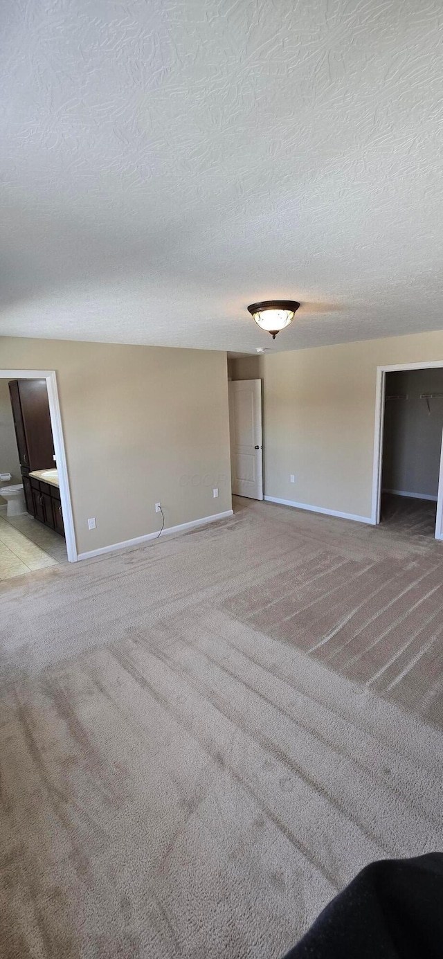 unfurnished room with carpet floors, baseboards, and a textured ceiling