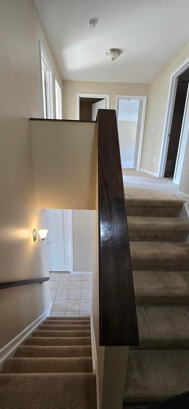 stairs featuring carpet flooring, tile patterned floors, and baseboards