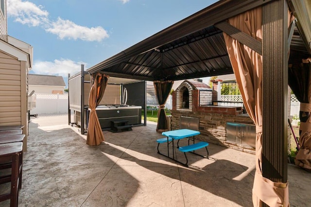 view of patio featuring fence, an outdoor kitchen, and a gazebo