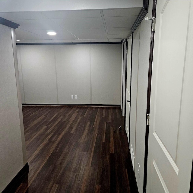 interior space with dark wood-type flooring and a paneled ceiling