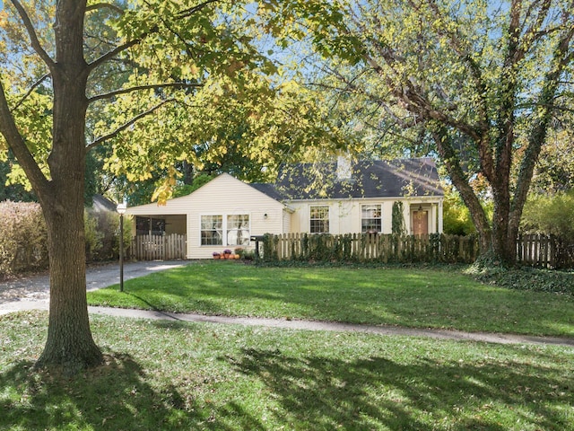 view of front facade featuring a carport, a front lawn, a fenced front yard, and driveway