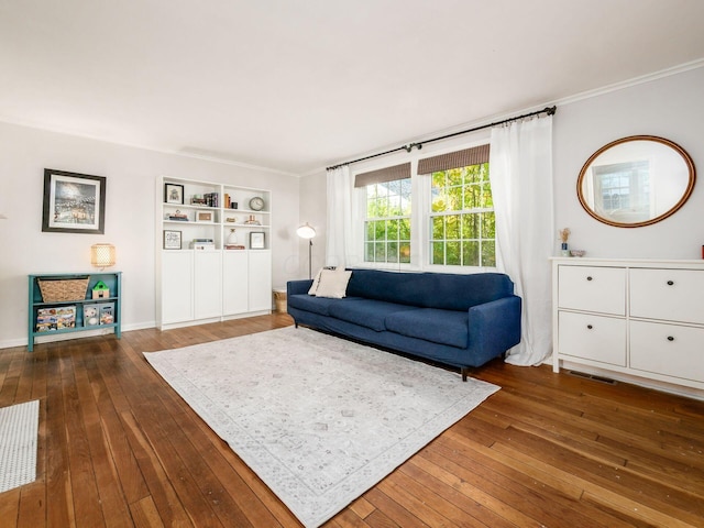 living area with ornamental molding, wood-type flooring, built in shelves, and baseboards