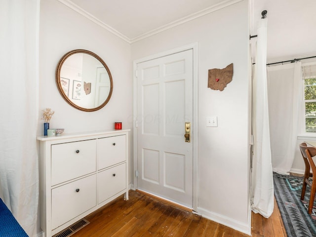 foyer featuring dark wood-type flooring, visible vents, crown molding, and baseboards