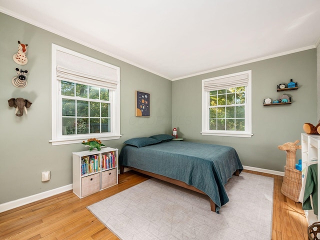 bedroom with ornamental molding, light wood-type flooring, multiple windows, and baseboards