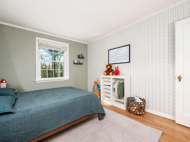 bedroom with wallpapered walls, crown molding, baseboards, and wood finished floors