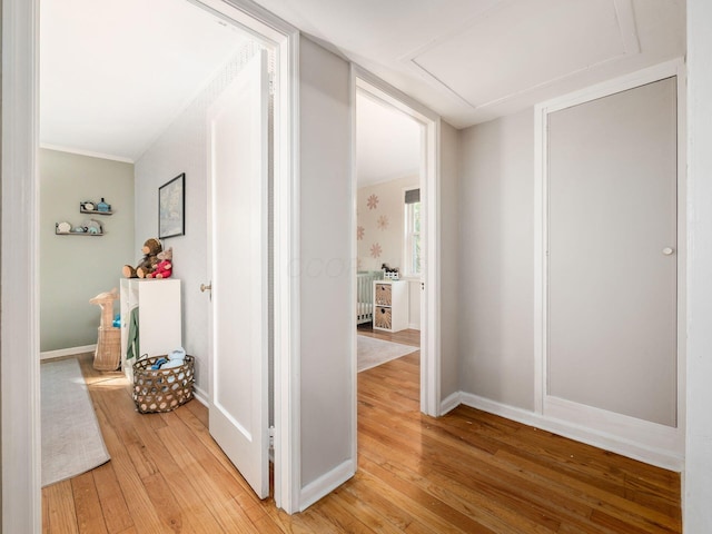 hall with light wood-style flooring and baseboards