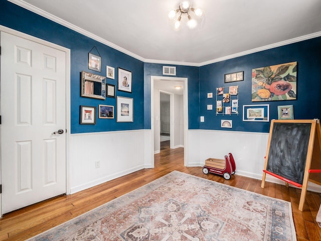 interior space featuring a wainscoted wall, a notable chandelier, visible vents, and hardwood / wood-style floors