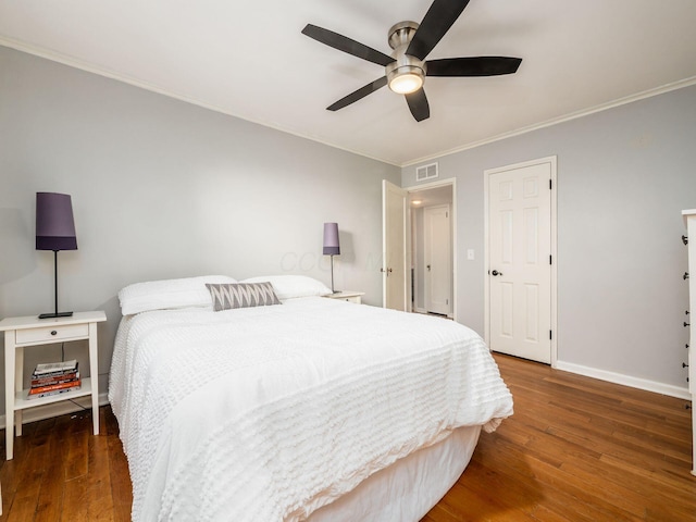 bedroom featuring baseboards, visible vents, wood finished floors, and ornamental molding