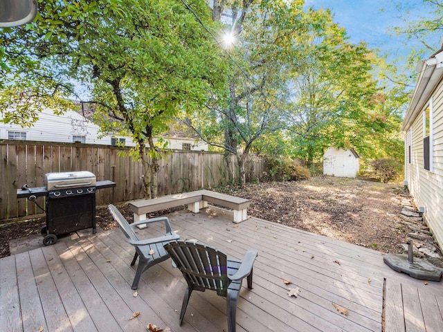 wooden deck featuring an outbuilding, a fenced backyard, grilling area, and a shed