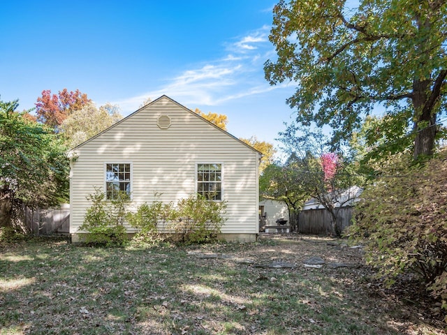 view of property exterior with a lawn and fence